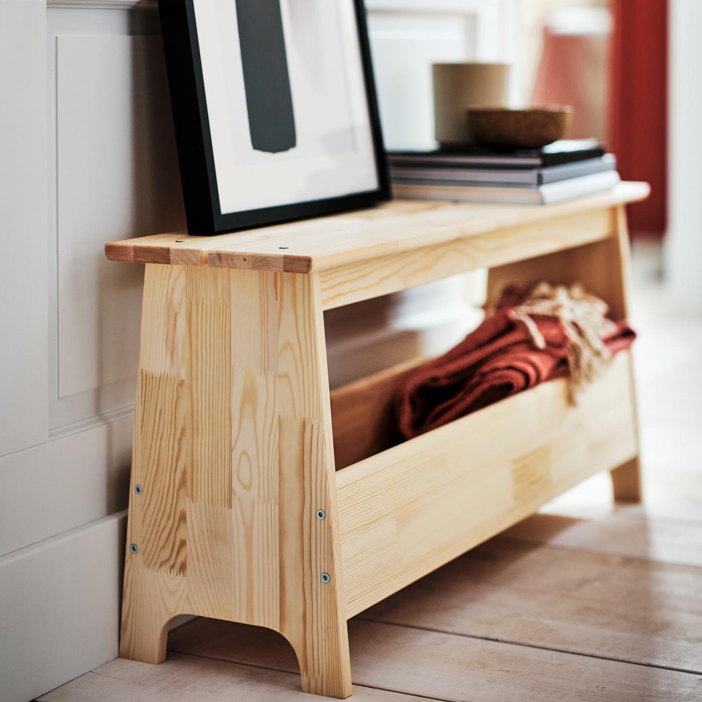 A BILD poster in a black RIBBA frame leaning against a wall on top of a pine PERJOHAN bench with storage.