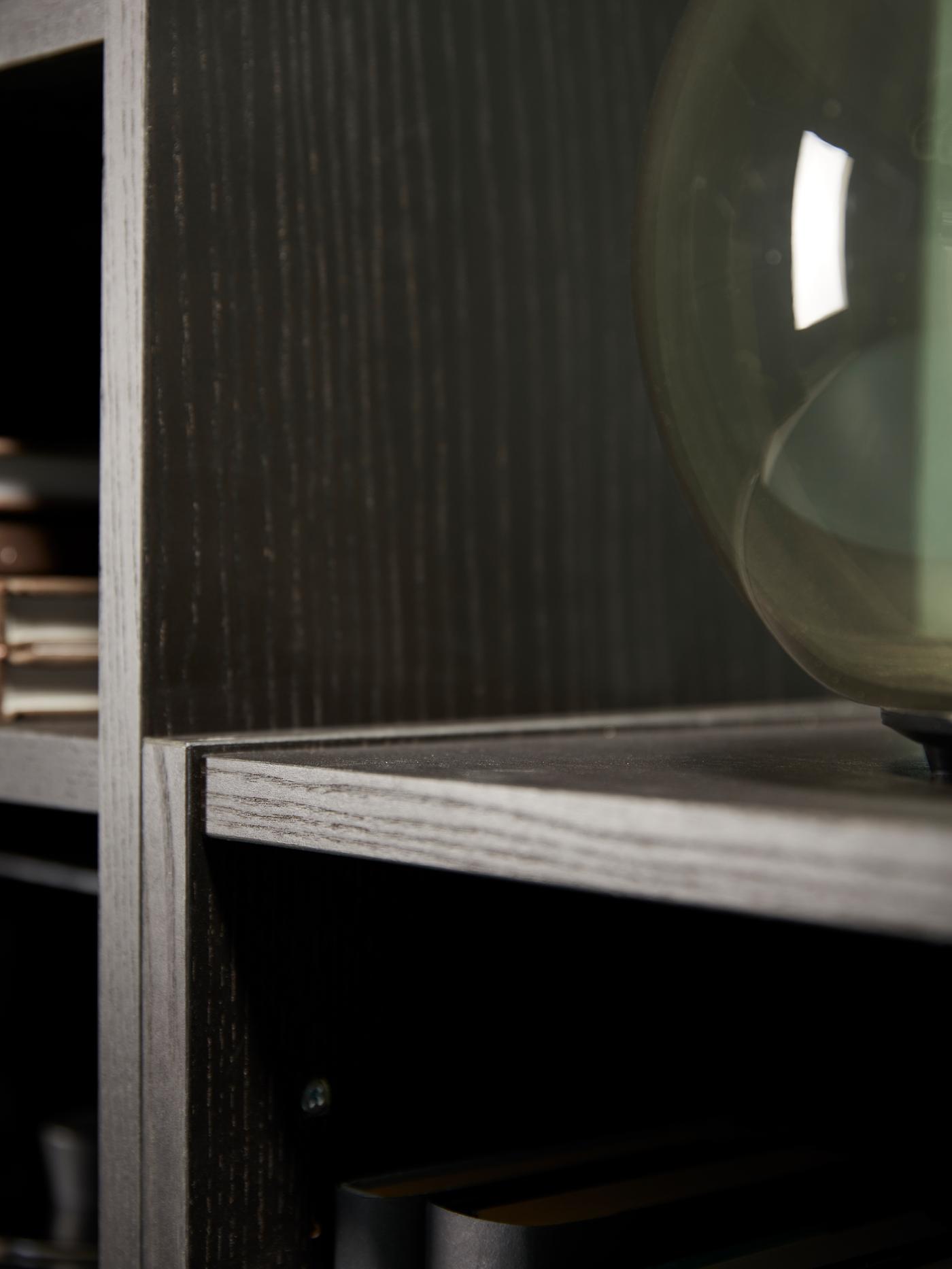 A BILLY bookcase in black/brown. On one of the shelves is a green glass vase.