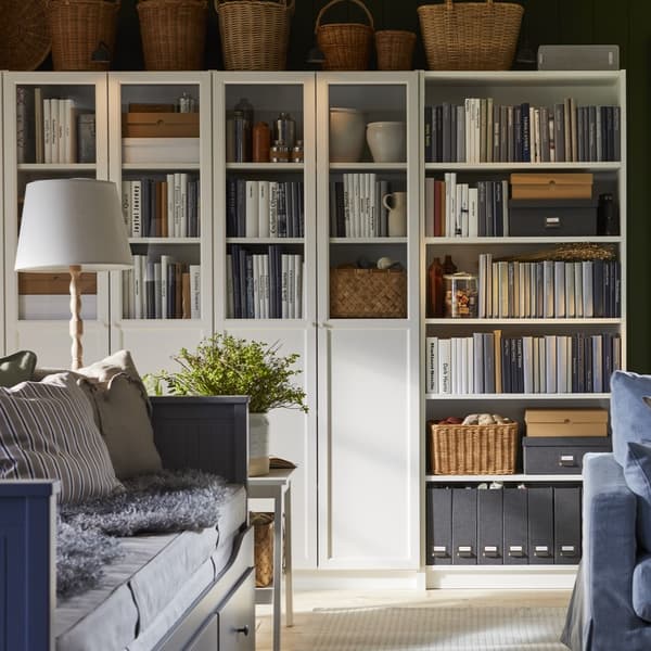 A BILLY shelving combination with various compartments, doors and shelves in white stands against a wall in the living room