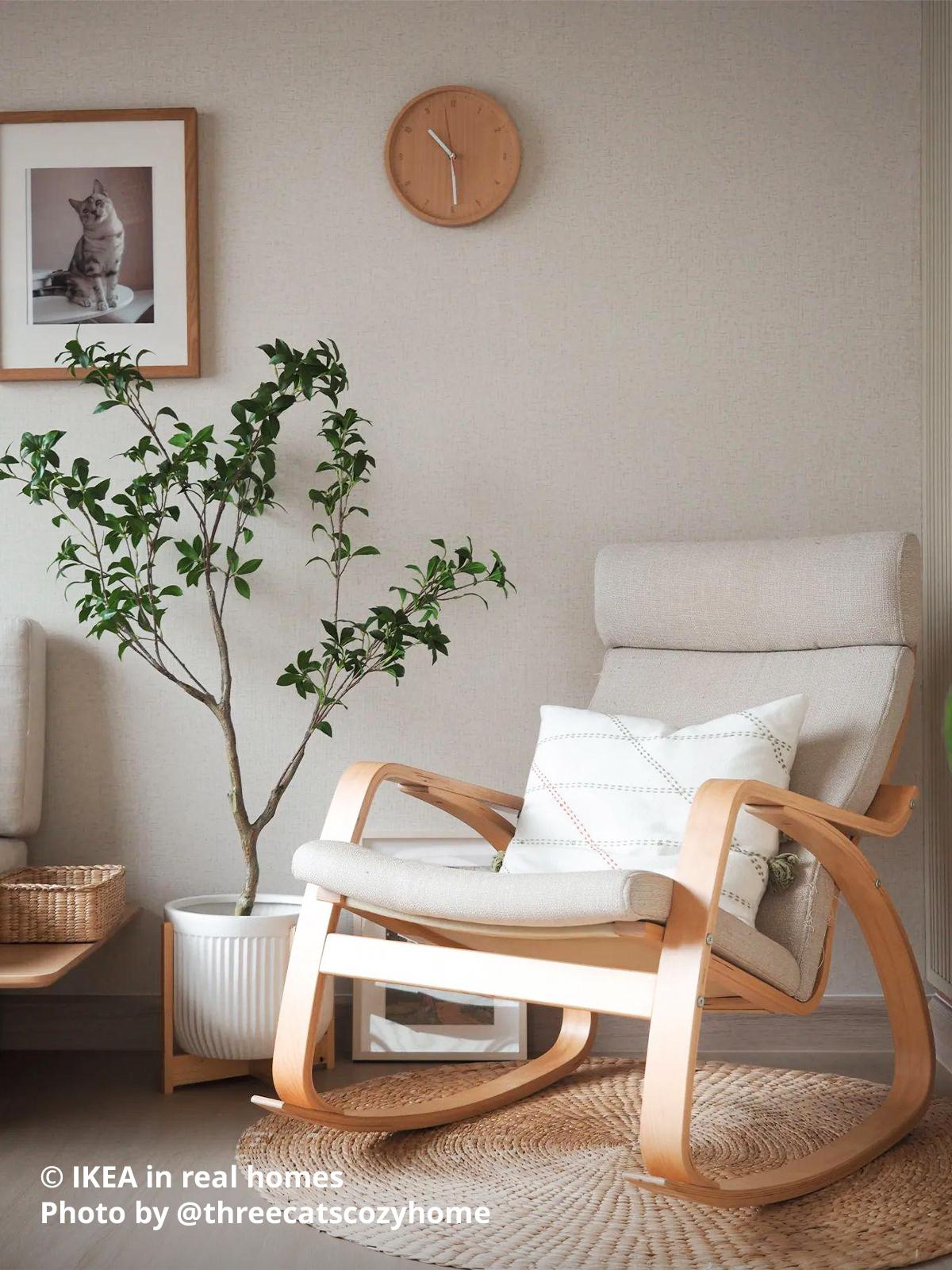 A birch veneer POÄNG rocking chair with hillared beige cushion cover placed right next to a pot of plant in the living room setting. Photo by instagrammer @threecatscozyhome for IKEA in real homes ©