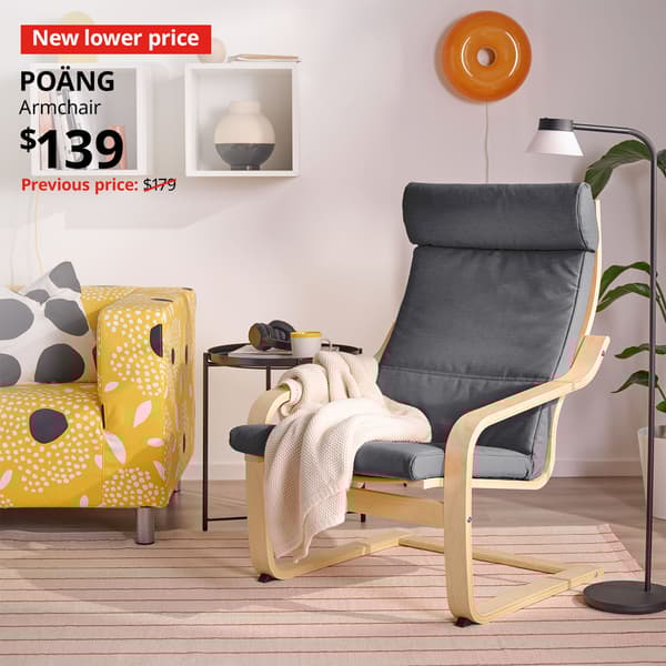A birch veneer/Skiftebo dark grey POÄNG armchair in a living room setting. A red "New lower price" label is on the top left of the image with black text that reads: POÄNG, Armchair, $139. Previous price with red slash $179.