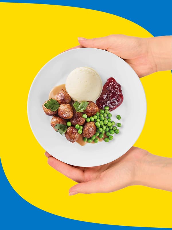 A birdeyes view of a meatball meal on a plate, blue and yellow background