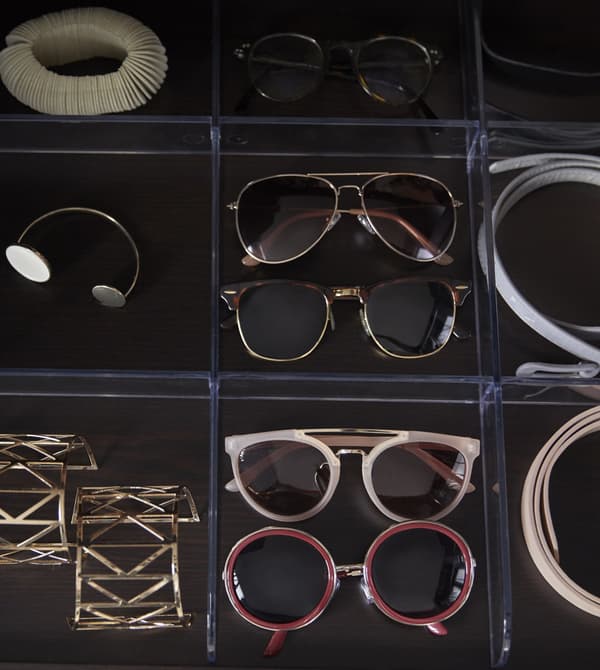 A bird’s-eye view of a wardrobe drawer insert that organizes sunglasses, jewelry, and belts.