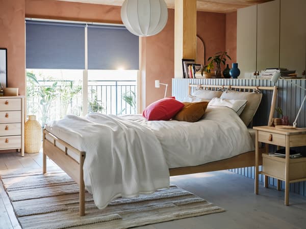 A BJÖRKSNÄS bed stands in a wood panelled room, while light streams through the window behind it.