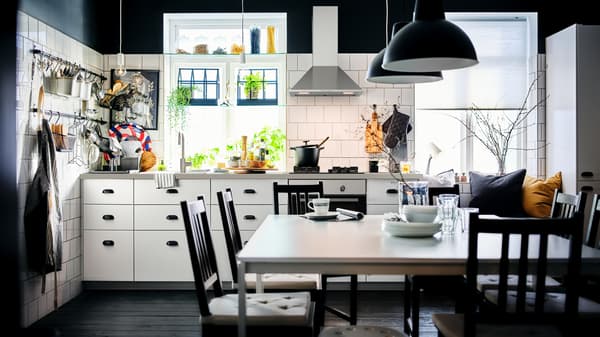 A black-and-white kitchen with white METOD cabinets with MAXIMERA interiors and a dining area with two white MELLTORP tables.