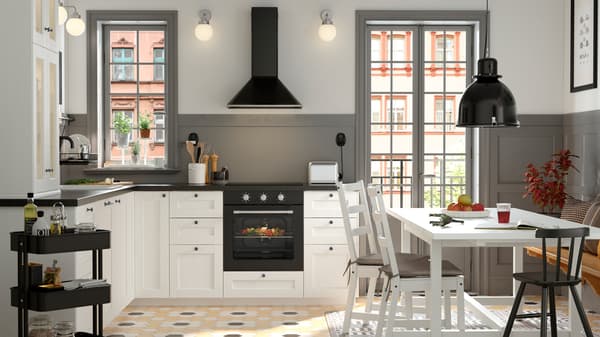 A black and white traditional-style kitchen with a white NORDVIKEN dining table surrounded by three chairs and a pine bench.