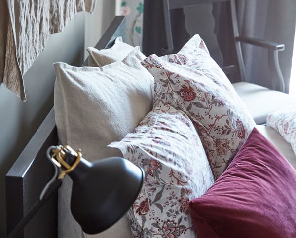 A black bed headboard with various pillows and cushions.