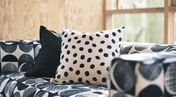 A black/beige KLIPPAN sofa with white spotted ODDNY printed cushion.