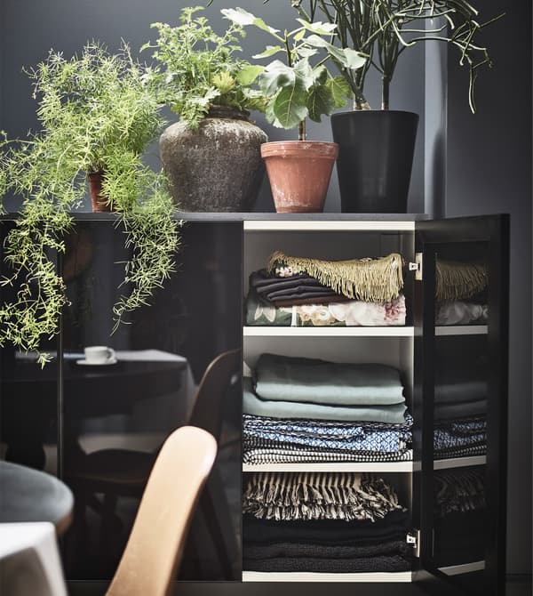 A black cabinet with smoky black glass doors opened to reveal linens.