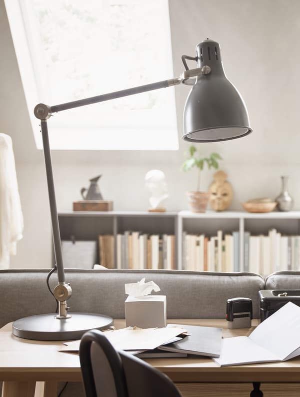 A black desk lamp sits on a desktop.