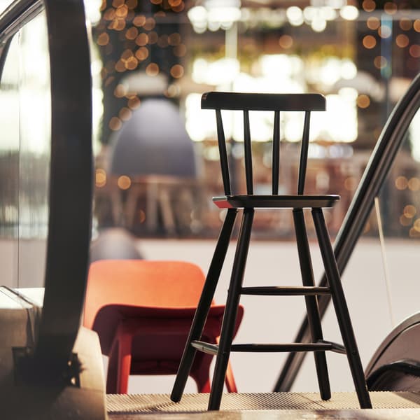 A black junior chair and a red dining chair going up an escalator.