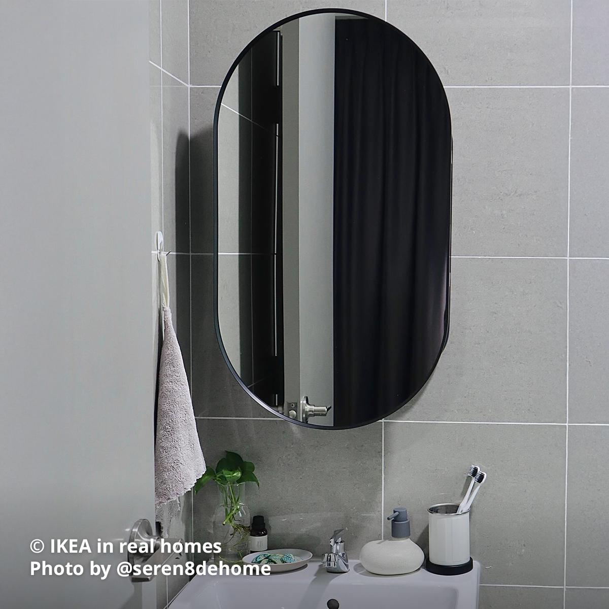 A black LINDBYN mirror with storage behind mounted above the sink is being used at the common toilet that has light grey square tiles and matching doors. Photo by instagrammer @seren8dehome from IKEA in real homes ©