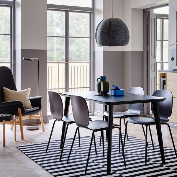 A black LISABO table and SVENBERTIL chairs in the centre of a room with grey and white walls and a storage unit.