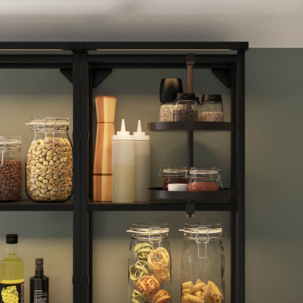 A black open shelf with integrated lighting, a swivel shelf, glass jars with pasta, different spice jars, oils and dressings.