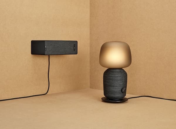 A black rounded speaker lamp next to a black wall mounted speaker.