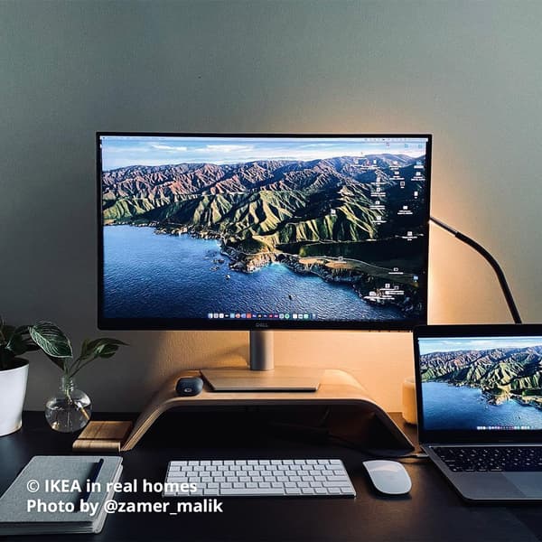 A black/silver HÅRTE LED work lamp is placed behind the laptop and a monitor screen is placed on top of a bamboo veneer SIGFINN monitor stand with keyboard and mouse, and on the left there is a notebook with a pen. Photo by instagrammer @zamer_malik from IKEA in real homes ©