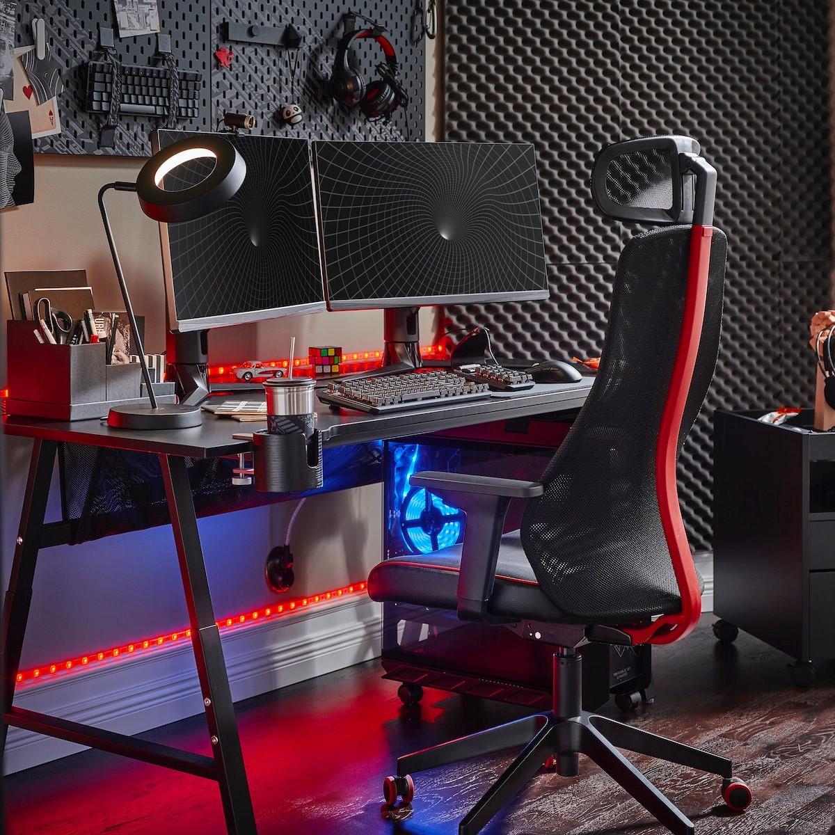 A black UTESPELARE gaming desk with two screens, a black gaming chair, a black drawer unit and various gaming accessories.