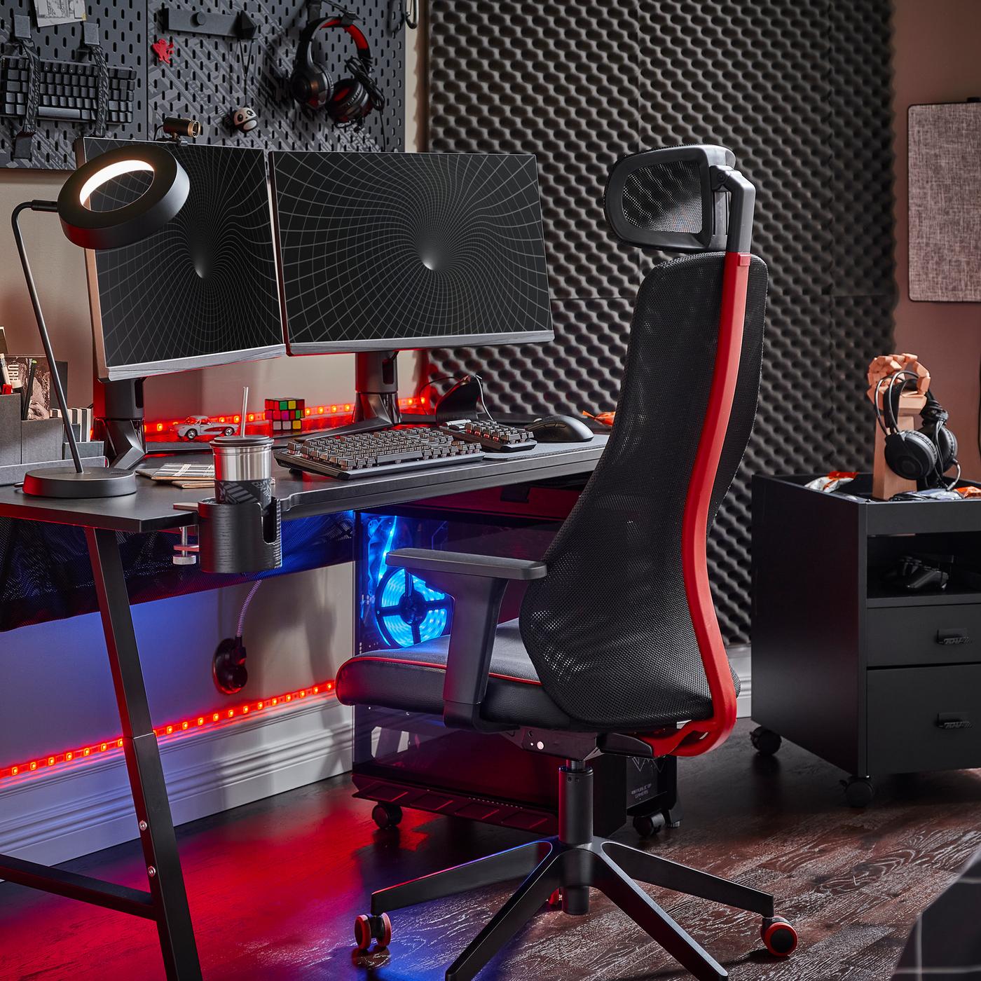 A black UTESPELARE gaming desk with two screens, a black gaming chair, a black drawer unit and various gaming accessories.