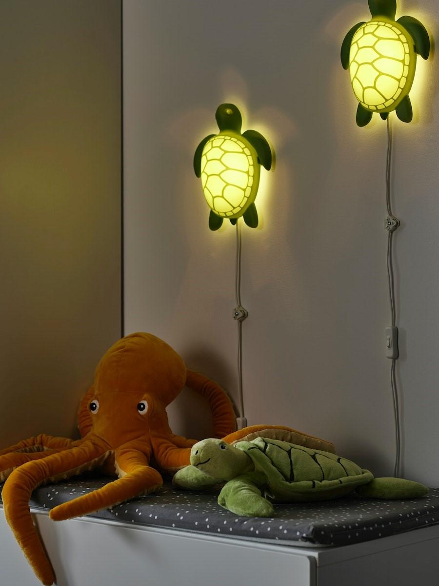 A BLÅVINGAD octopus-shaped night-light is switched on in a dim room; a BLÅVINGAD turtle-shaped LED wall lamp is lit above it.