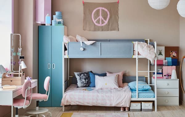 A blue and pink children's room for siblings with a white bunk bed, a white shared desk and light pink desk chairs.