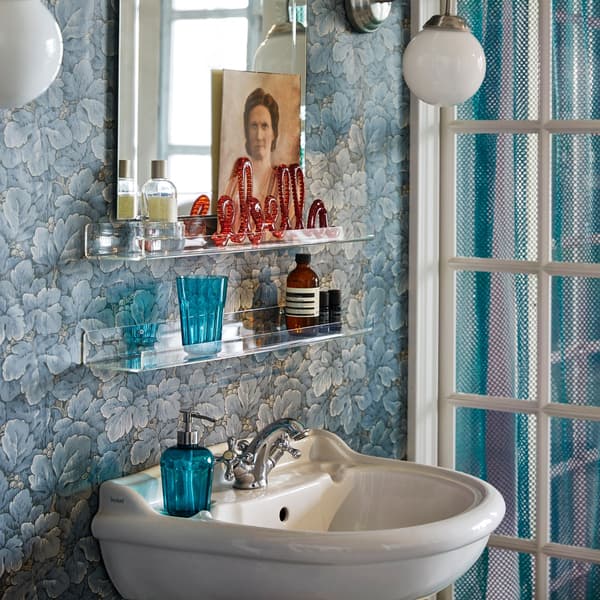 A blue bathroom sink and mirror area with a shelf displaying bathroom accessories.