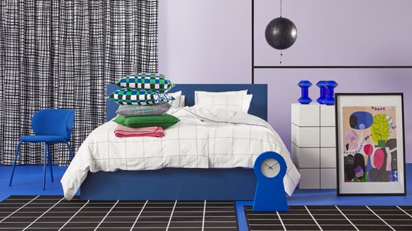 A blue bed with multi-colour pillows, blue chair, blue clock, blue vases and picture in frame