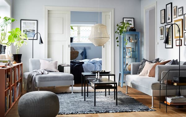 A blue, grey and orange living room with a DELAKTIG chaise longue with side table and floor lamp and 3-seat sofa in white/black.