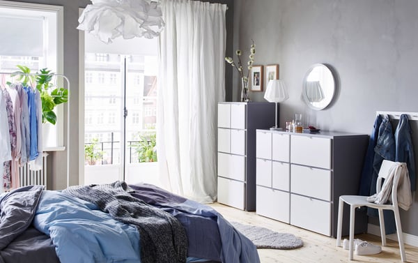 A blue, grey, and white bedroom with two IKEA VISTHUS white chest-of-drawers side by side.