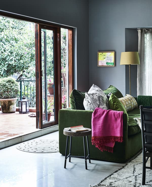 A blue living room with brightly coloured textiles.