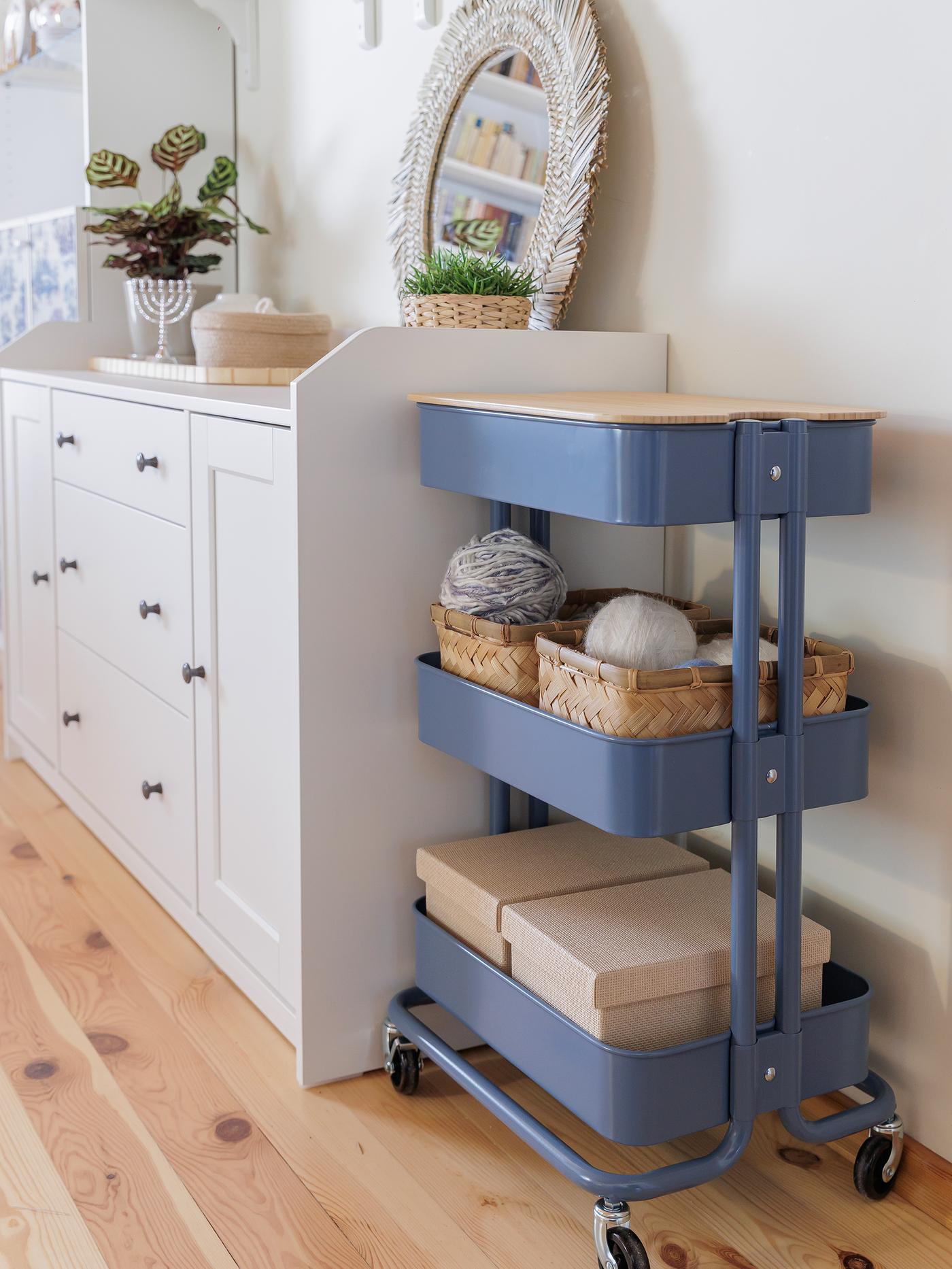 A blue RÅSKOG trolley stands beside the sideboard, featuring two shelves with neatly arranged baskets and containers.