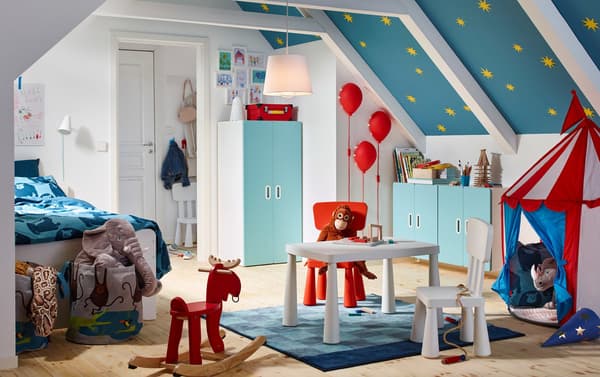 A blue, red and white circus themed children’s bedroom with STUVA/FRITIDS wardrobe in white and light blue.