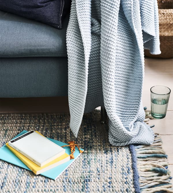 A blue sofa with blue blanket on a blue rug.
