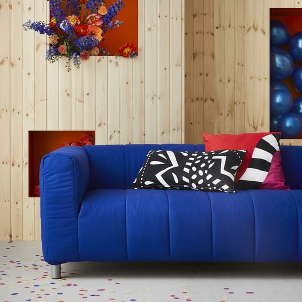 A blue sofa with patterned cushions in a wood-panelled room.