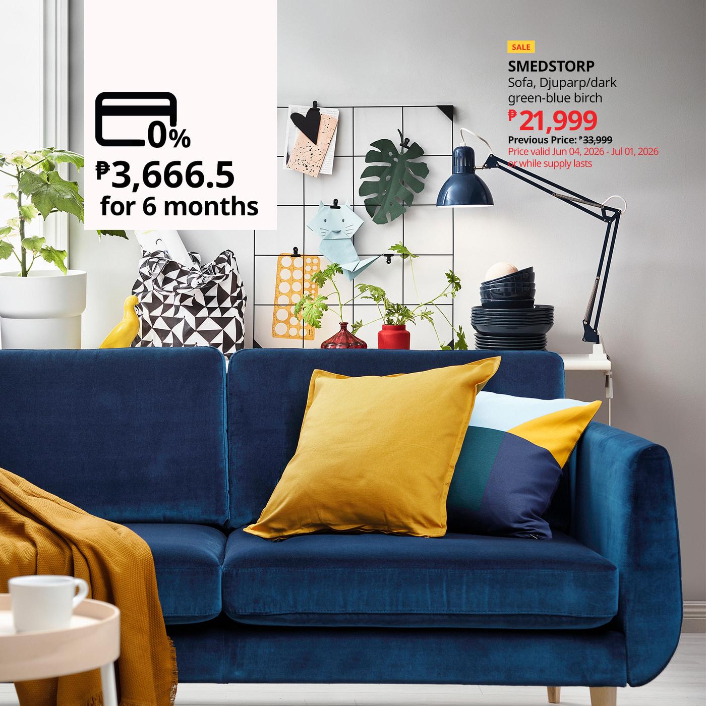A blue sofa with yellow and blue cushions in a living room, next to a side table with plants and decorative items. Text advertises a 6-month installment plan for the sofa.