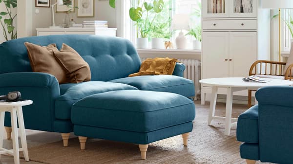 A blue traditional sofa in a bright living room.