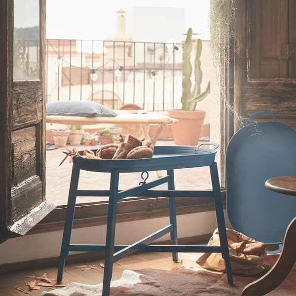 A blue tray table in front of wooden balcony doors.