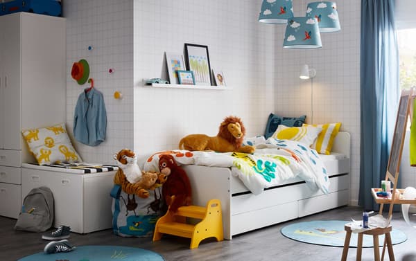 A blue, white and yellow jungle theme children’s bedroom with SLÄKT bed with pull-out bed and storage.