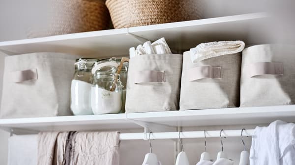 A BOAXEL system of white shelves, with glass jars containing washing powder and PURRPINGLA storage boxes.