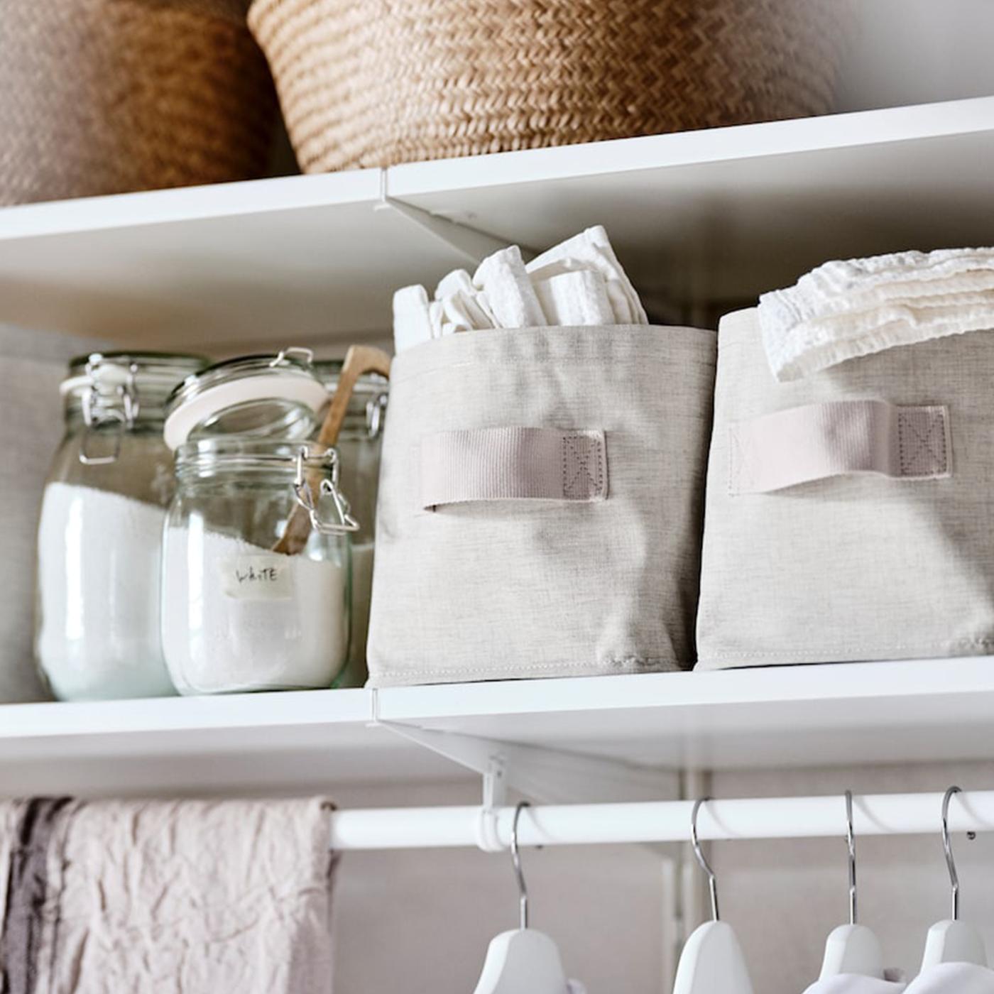 A BOAXEL system of white shelves, with glass jars containing washing powder and PURRPINGLA storage boxes.