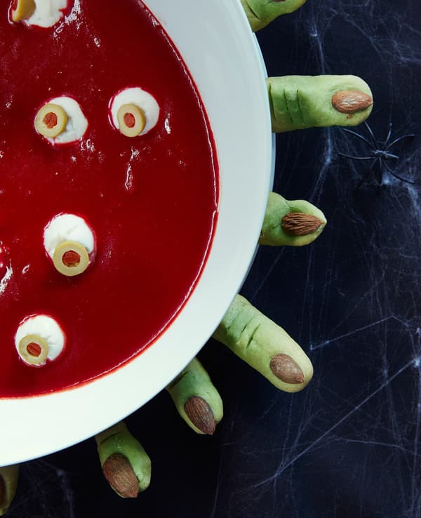 A bowl of red soup with mozzarella balls is surrounded by shortbread that looks like witch fingers.