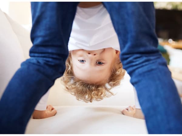 A boy standing on all fours on a white couch while playing, symbolising product safety at IKEA.