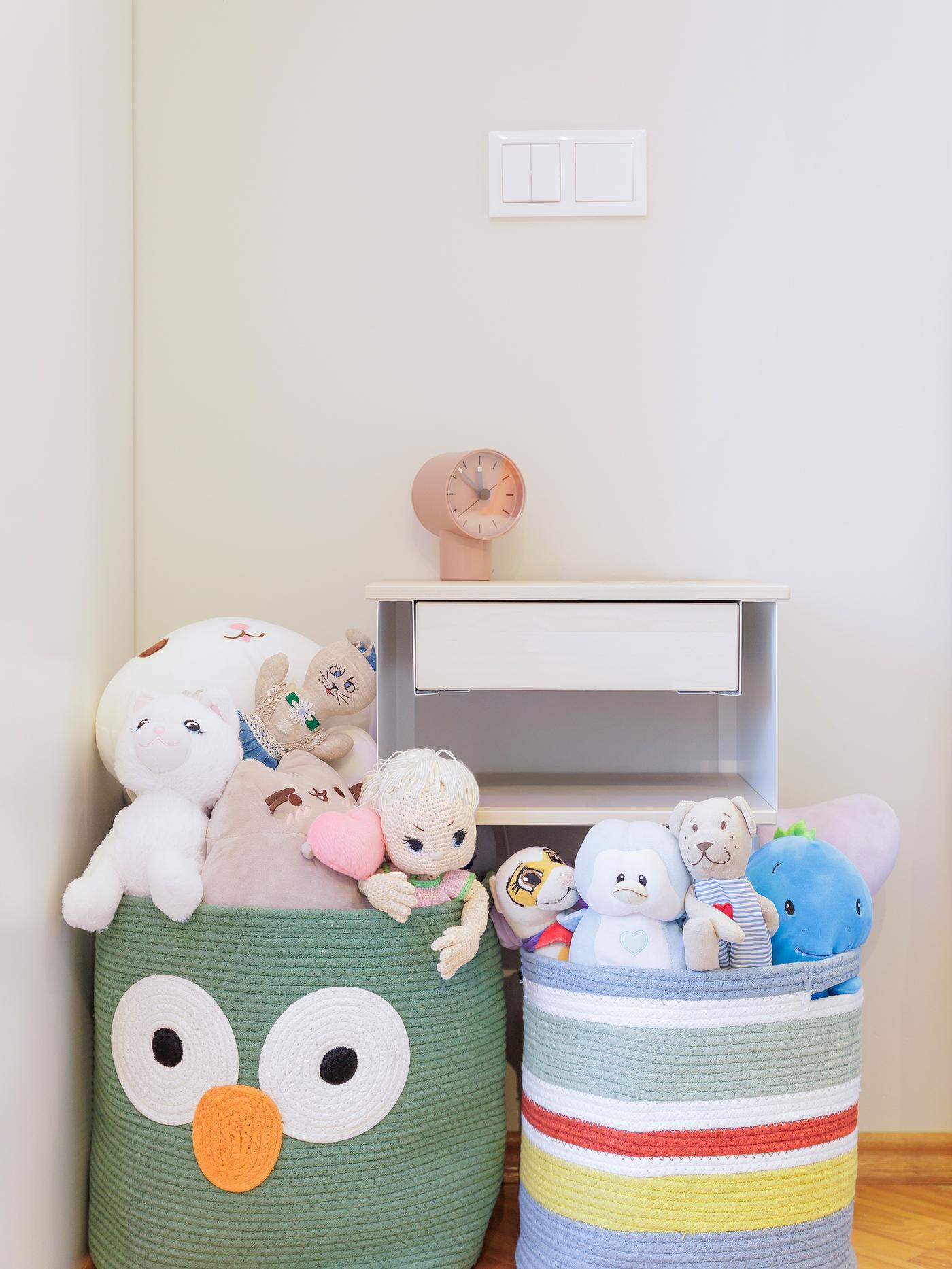 A braided UPPSTÅ storage bag designed like a colourful owl, filled with stuffed animals and toys.