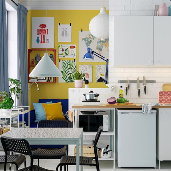 A bright and small kitchen area with white ENHET kitchen combination, white dining table and four black chairs.