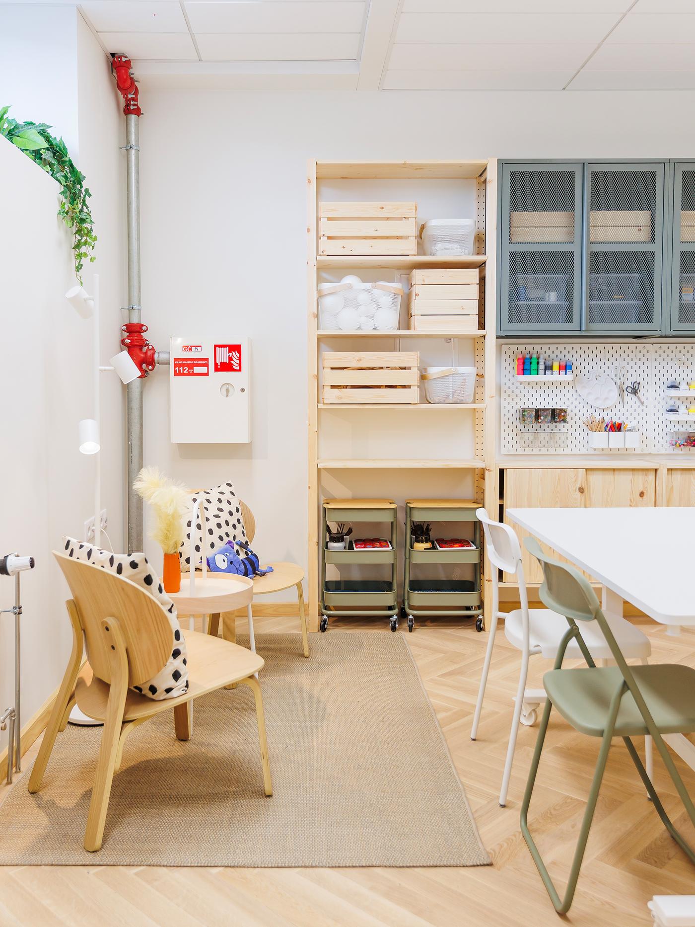 A bright art studio with wooden shelves, tables and chairs arranged neatly.