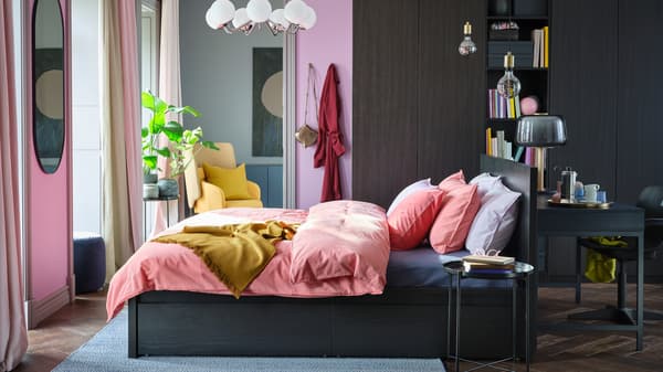 A bright bedroom with a black-brown MALM bed, colourful bedding, and a large PAX/FORSAND wardrobe on one wall.