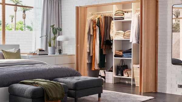 A bright bedroom with a fitted AURDAL wardrobe, a white MALM bed with gray bedding and two dark gray MORABO footstools.