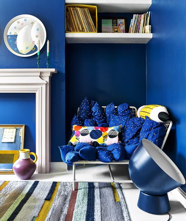 A bright blue living room with sofa, oversized lighting and rug.
