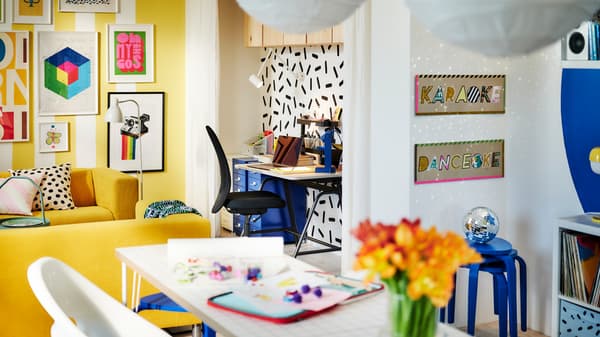 A bright, colorful, spacious room. A workspace with a GLADHÖJDEN sit-stand desk is placed along a graphic-patterned wall.
