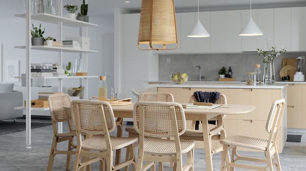 A bright dining area with bamboo and paper loom dining table and chairs, a white room divider and a kitchen island.