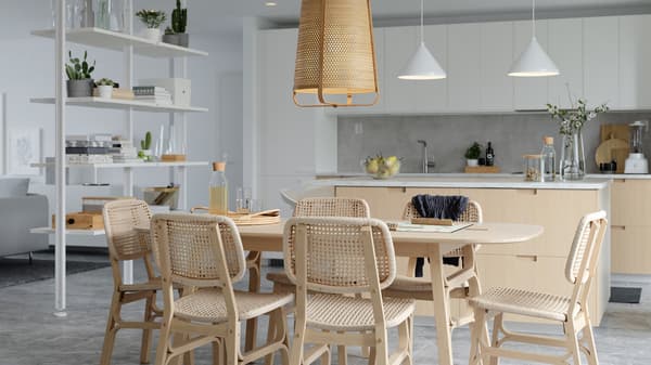 A bright dining area with bamboo and paper loom dining table and chairs, a white room divider and a kitchen island.